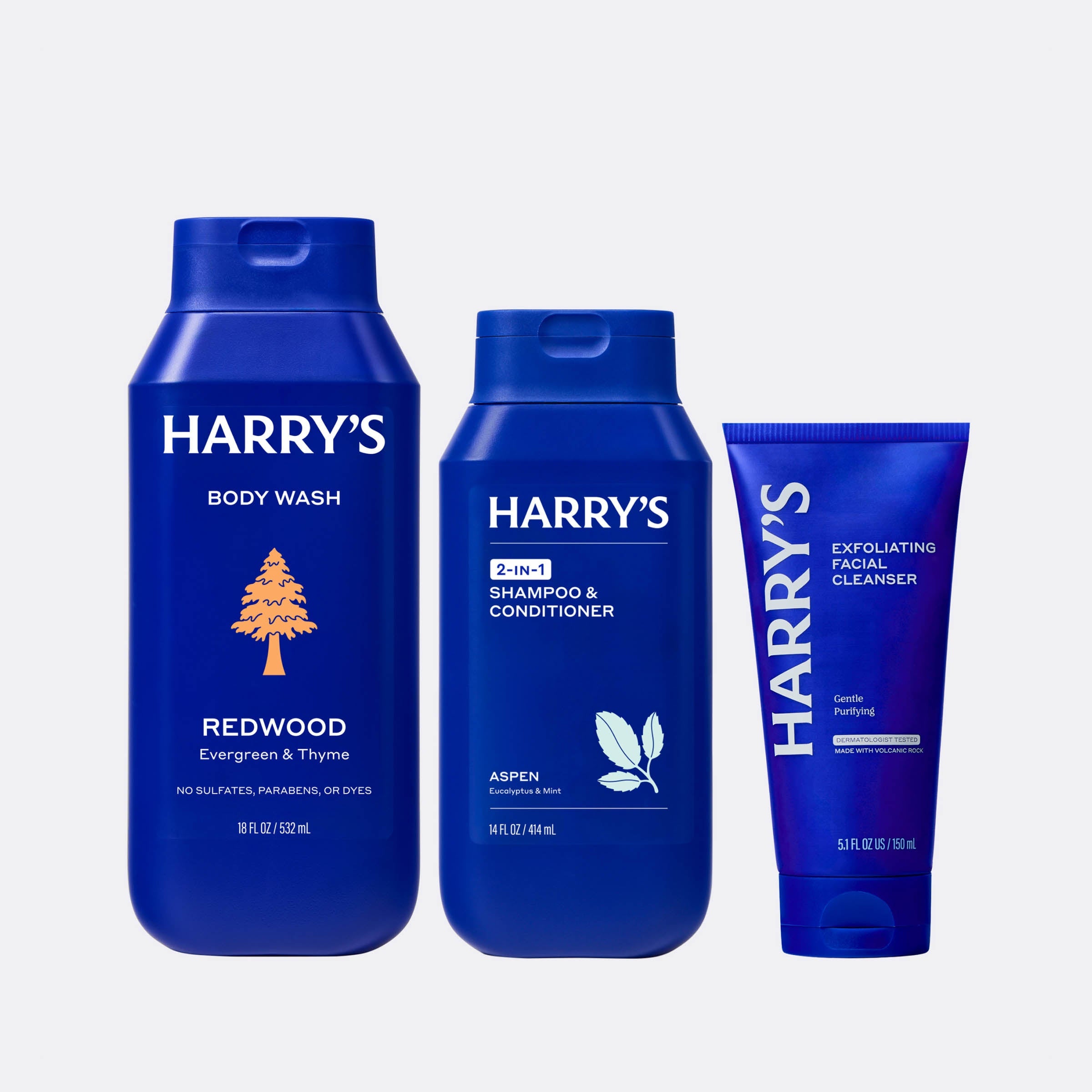Three blue bottles of Harry's grooming products on a white background